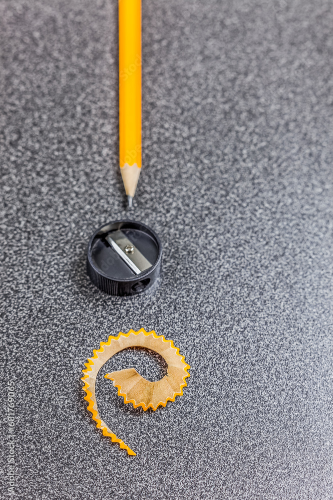 Pencil, pencil sharpener and pencil shaving on desk, close-up
