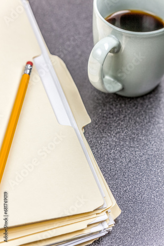 File folders and pencil on a desk with a cup of coffee