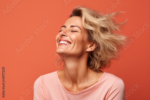 Portrait of beautiful young woman with flying hair over orange background. photo