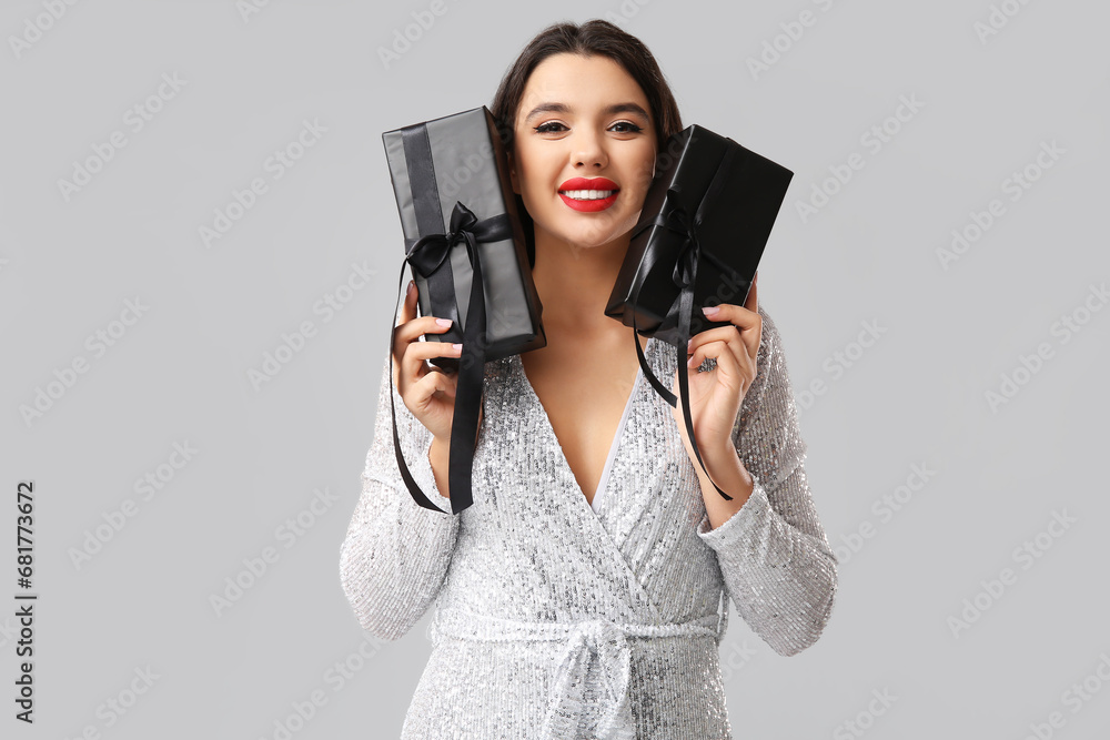Beautiful young woman with gift boxes on grey background. Black Friday sale Beautiful young woman with gift boxes on grey background. Black Friday sale