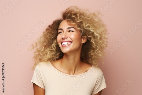 Portrait of young happy smiling woman with curly hair over pink background