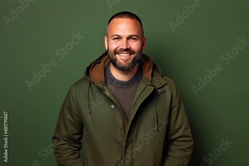 Portrait of a handsome smiling man in a warm jacket against green background