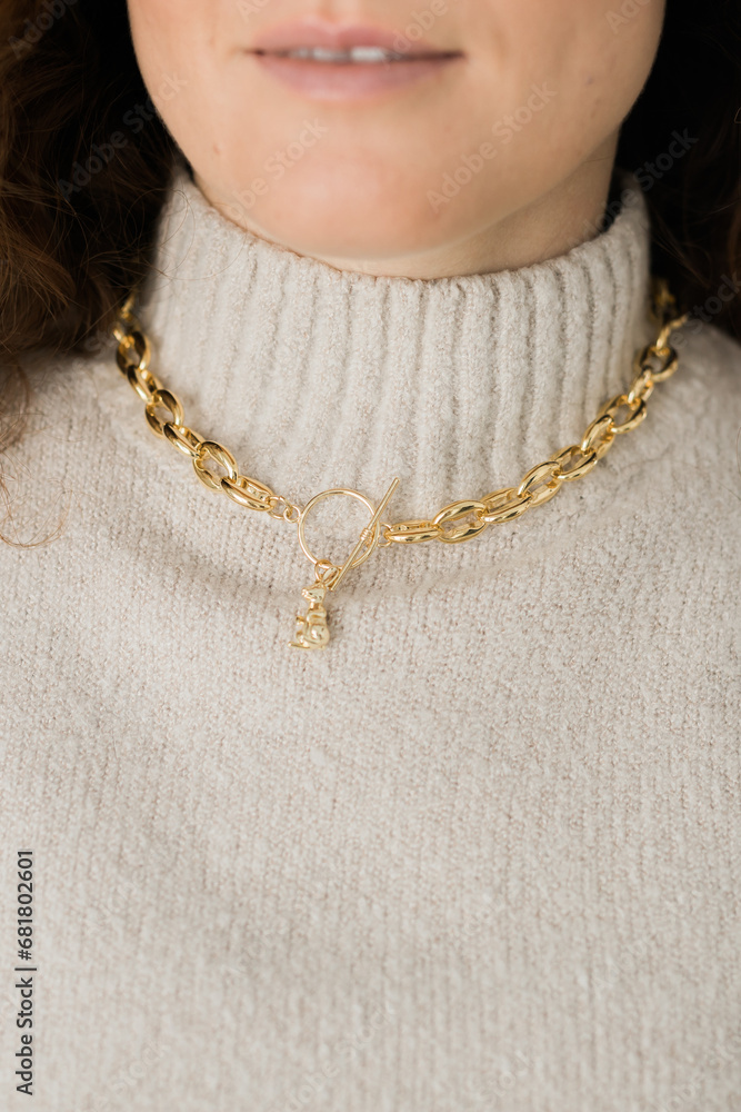 Close-up female in modern gold metal necklace chain with gold bunny pendant Close-up female in modern gold metal necklace chain with gold bunny pendant