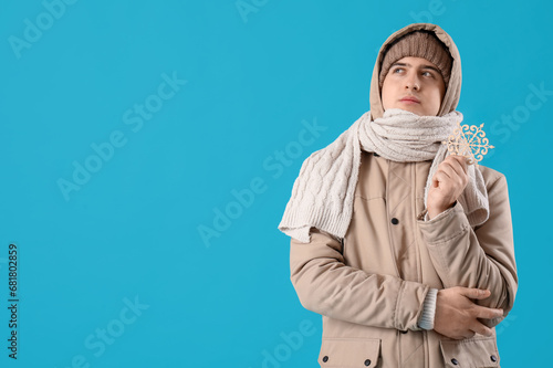 Young man in winter clothes with snowflake on blue background