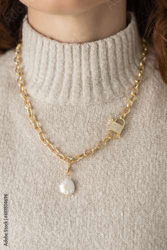 Close-up female in modern gold metal necklace chain with pearl pendant