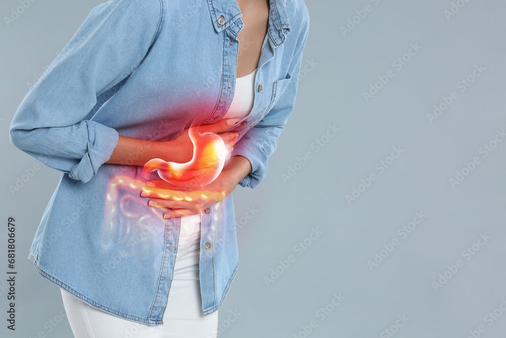 Woman suffering from stomach ache on grey background, closeup with space for text. Illustration of unhealthy gastrointestinal tract - obrazy, fototapety, plakaty 