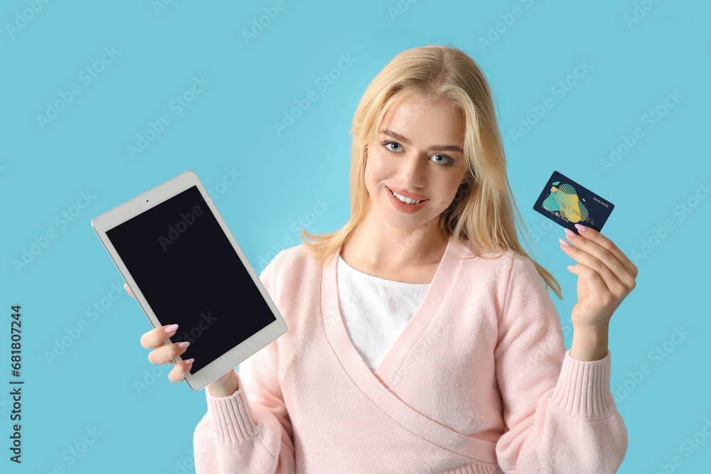 Young woman with modern tablet computer and credit card on color background