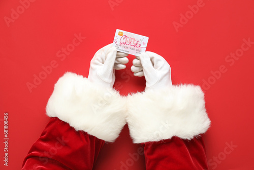 Papier peint Santa hands with gift card on red background, closeup