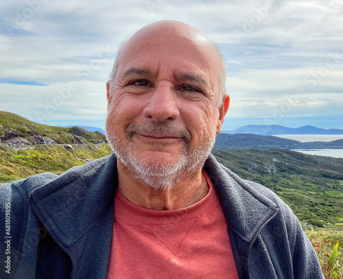 Bald, smiling senior with a country side background