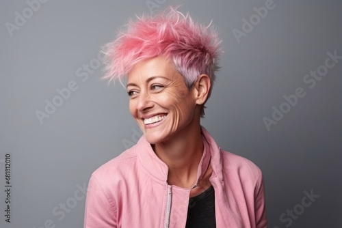 Portrait of a happy senior woman with pink hair over grey background