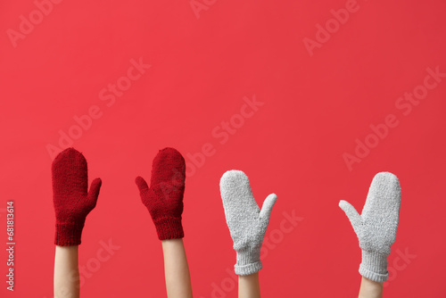 Female hands in stylish warm mittens on red background