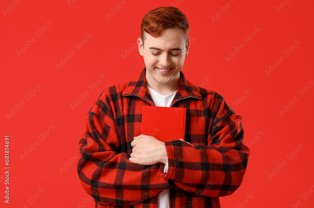 Happy young man with book on red background Happy young man with book on red background