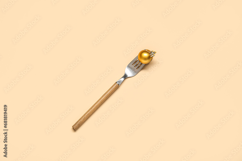 Fork with Christmas ball on beige background Fork with Christmas ball on beige background