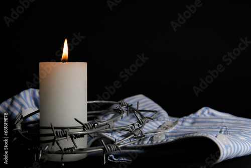 Foto Burning candle with barbed wire and prisoner uniform on dark background, closeup
