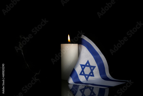 Burning candle with flag of Israel and barbed wire on dark background. International Holocaust Remembrance Day photo