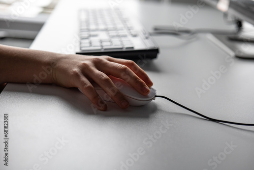 Close-up of a woman's hand using a mouse on a desk