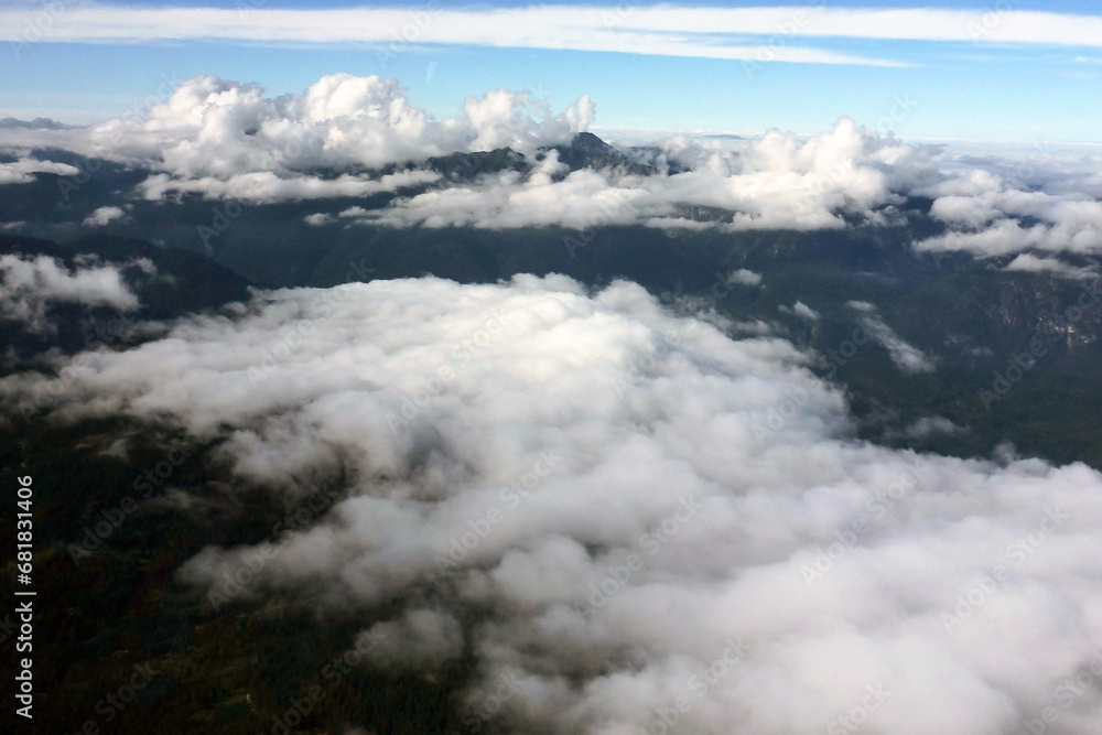 View through white clouds to mountain peaks and blue sky above them View through white clouds to mountain peaks and blue sky above them