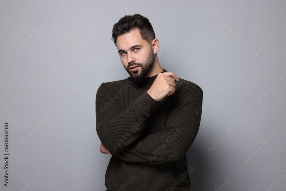 Handsome man in stylish sweater on grey background