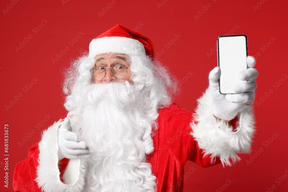 Merry Christmas. Santa Claus showing smartphone on red background