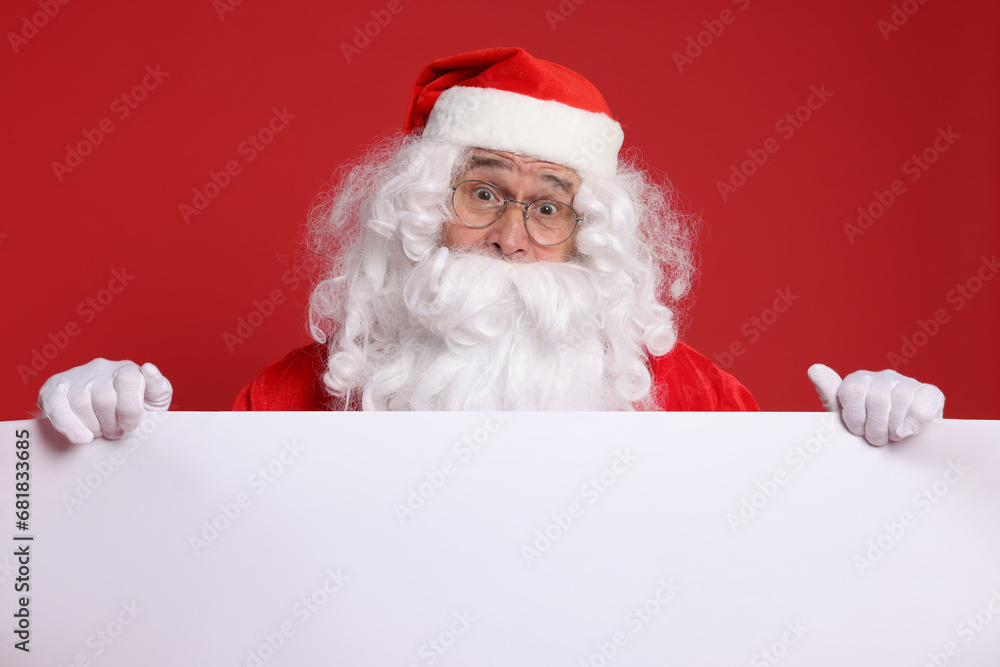Surprised Santa Claus holding blank poster on red background. Space for text Surprised Santa Claus holding blank poster on red background. Space for text