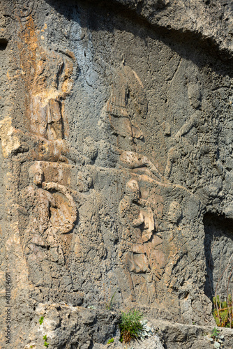 Closeup of reliefs carved in stone cliff near ancient Lycian rock tombs in Tlos city, Mugla Province, Turkey photo