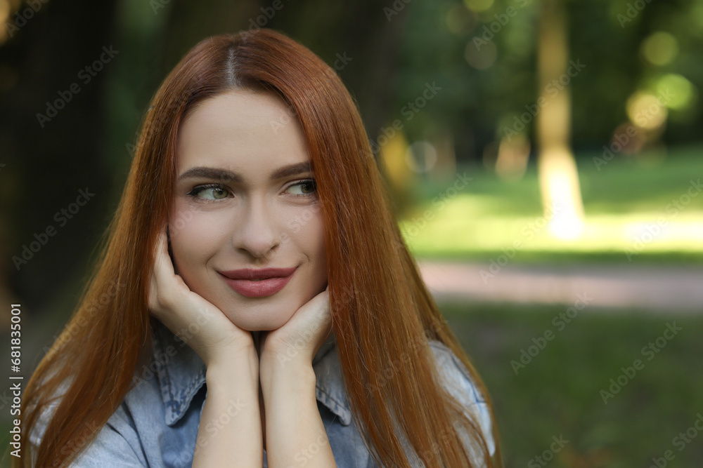 Portrait of beautiful young woman with red hair outdoors. Space for text. Attractive lady posing for camera Portrait of beautiful young woman with red hair outdoors. Space for text. Attractive lady posing for camera