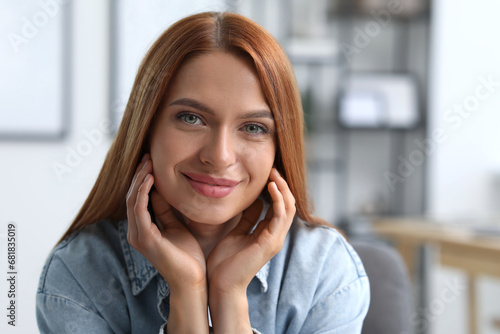 Portrait of beautiful young woman with red hair indoors. Attractive happy lady looking into camera. Space for text