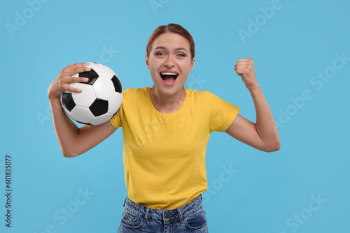 Emotional fan holding football ball and celebrating on light blue background © New Africa