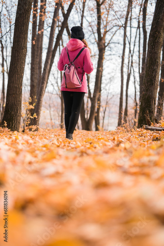 Back view of a girl walking on autumn park in fall season. Generation Z and gen z youth. Copy empty space for text.