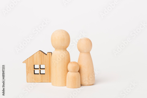 Wooden family figures with house on color background