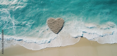 An aerial view of a heart drawn in the sand of a secluded beach, with the waves of the turquoise ocean gently erasing the edges, capturing a moment of tranquility. photo