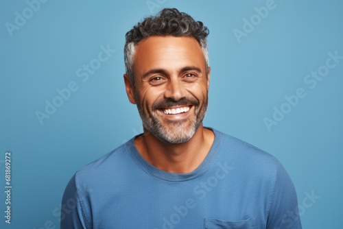 Handsome middle aged man smiling and looking at camera against blue background