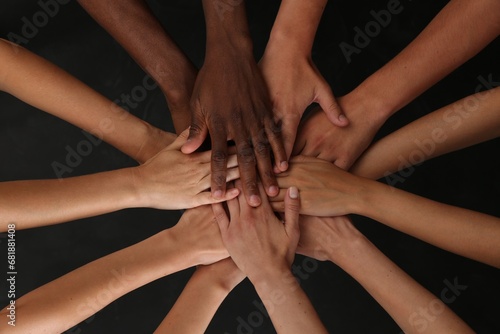 Group of multiracial people joining hands together on black background, closeup photo