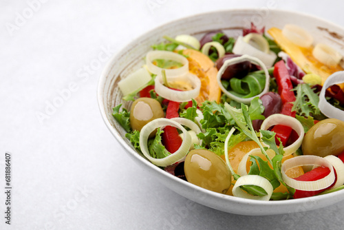 Bowl of tasty salad with leek and olives on light table, closeup. Space for text