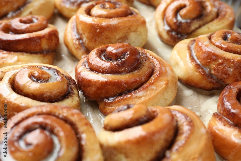 Tasty cinnamon rolls with cream on parchment paper, closeup Tasty cinnamon rolls with cream on parchment paper, closeup