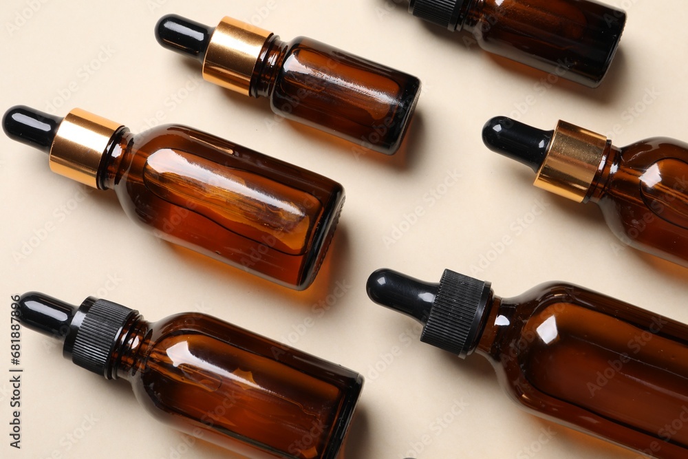 Many bottles with face serums on beige background, above view Many bottles with face serums on beige background, above view