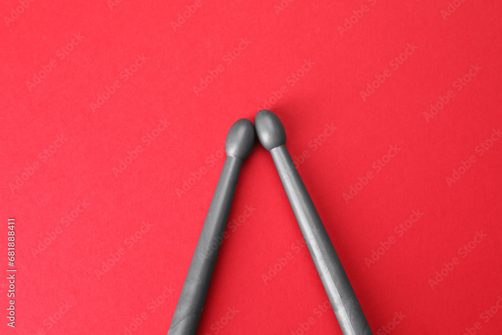 Two gray drum sticks on red background, top view