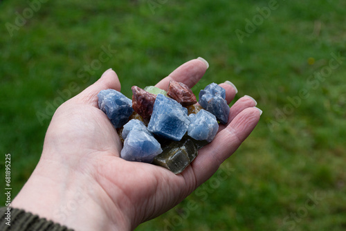 An image of a hand holding various calcite crystals used in energy healing.  photo