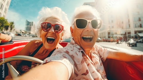 Happy old couple driving an old timer cabrio through an touristic town on their vacation
