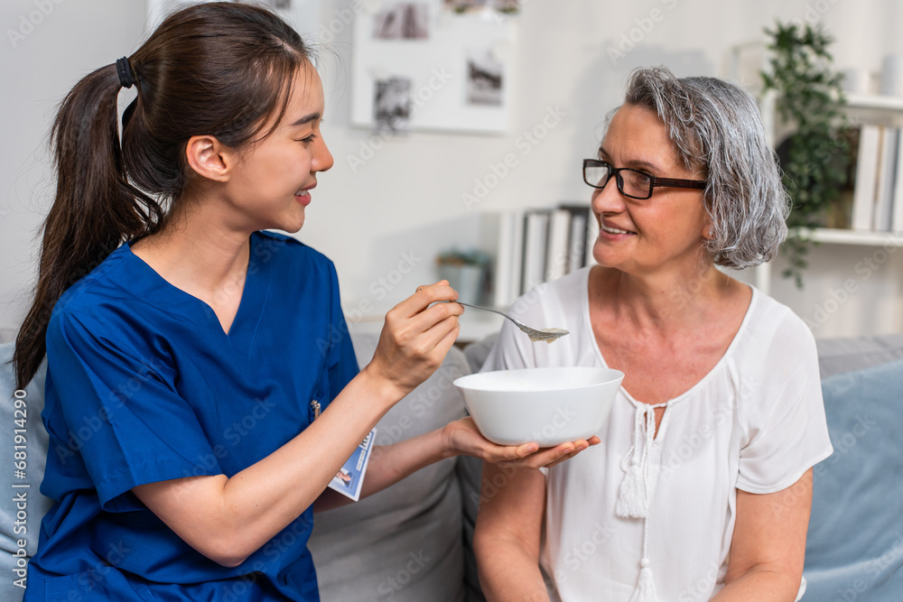 Asian caregiver nurse serve food to Caucasian senior older woman at home. Asian caregiver nurse serve food to Caucasian senior older woman at home.