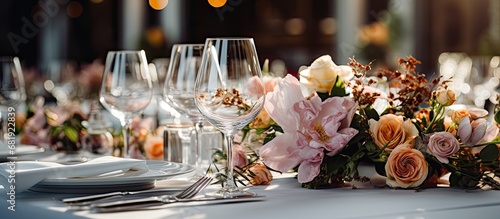 In the luxurious interior of a restaurant, a white tablecloth adorned with vibrant flowers sets the stage for a romantic wedding celebration. The table, beautifully decorated with silverware and photo