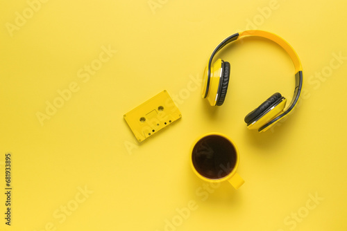 Monochrome image of a yellow coffee cup, cassette tape and headphones on yellow. Space for text. photo
