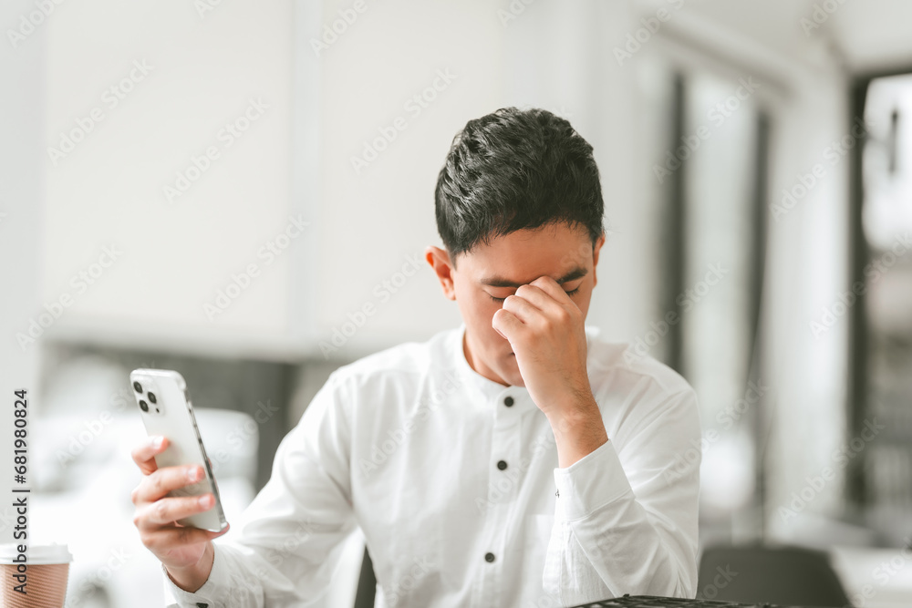 Asian male people concerned person in white shirt looks at laptop, possibly stressed, hand on their forehead. middle age businessman Asian male people concerned person in white shirt looks at laptop, possibly stressed, hand on their forehead. middle age businessman