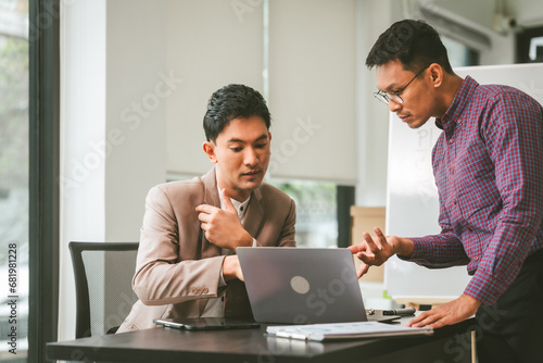 Two professionals in meeting, one presenting "Business, Plan, Success" on whiteboard, another observing and holding a clipboard. Asian businessman, Colleagues, Middle-age © Ratirath