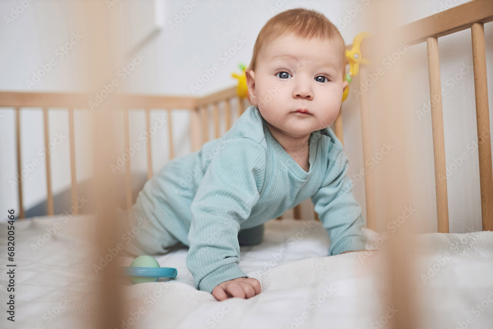 Close up of cute baby boy with blue eyes looking at camera while crawling in crib, copy space Close up of cute baby boy with blue eyes looking at camera while crawling in crib, copy space