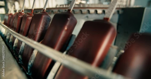 Portions of chocolate ice cream on a conveyor belt. Refrigeration plant, production of ice cream on a stick.