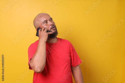 Bearded bald man talking on the phone while looking away