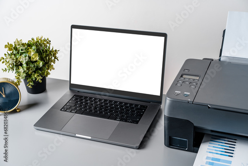 Printer and laptop on grey table in office