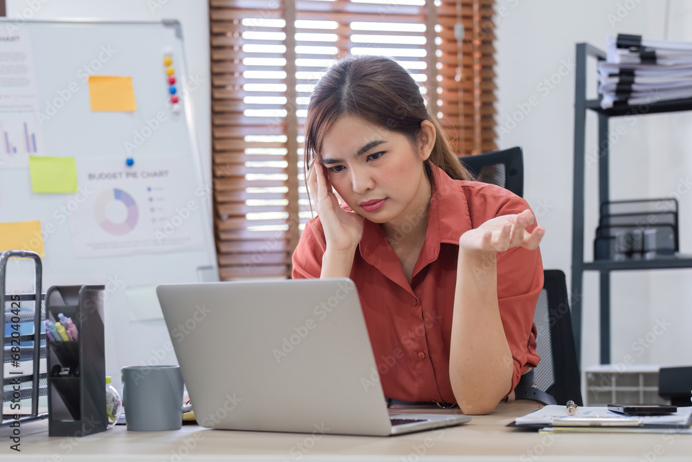 Tired and stress Asian woman Thinking hard about how to solve online problems looking at laptop screen. Serious Asian businesswoman worried focused on solving difficult computer tasks