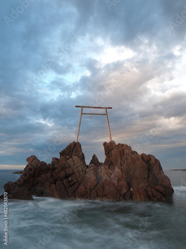 夕焼けの空と岩の上に建造された鳥居
